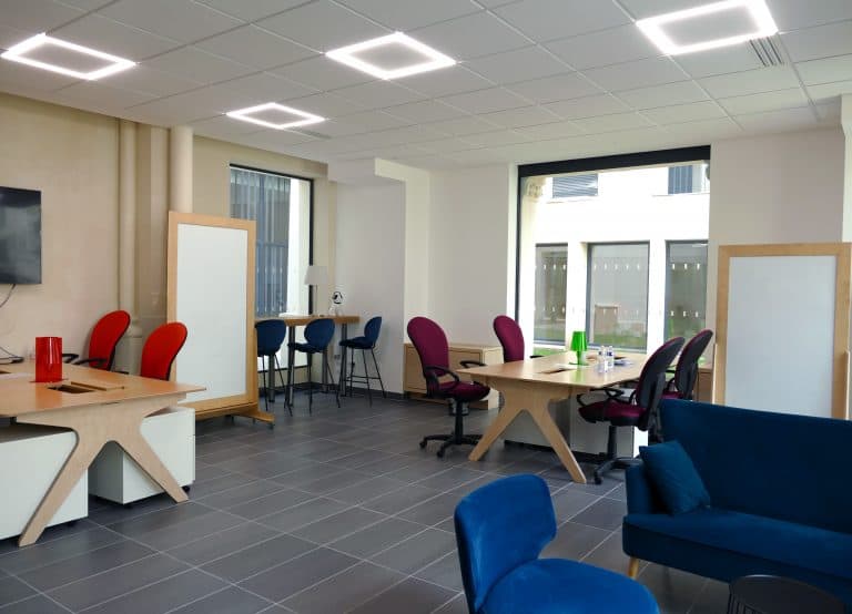 Salle de coworking avec des bureaux, chaises et paperboards