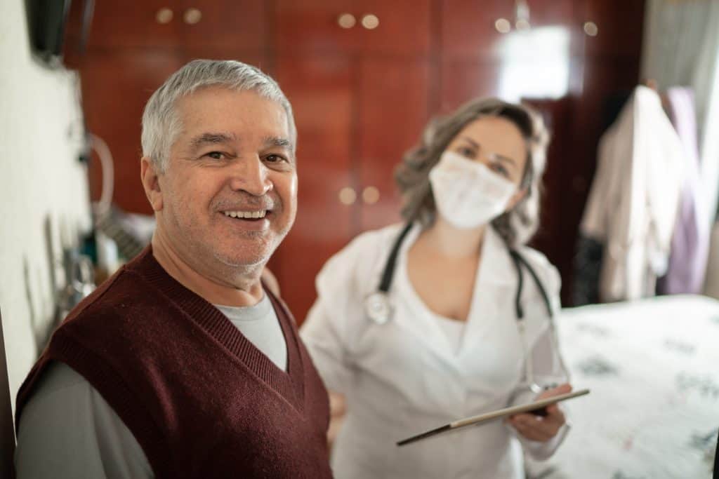 Portrait Of Health Visitor And Senior Man During Home Visit