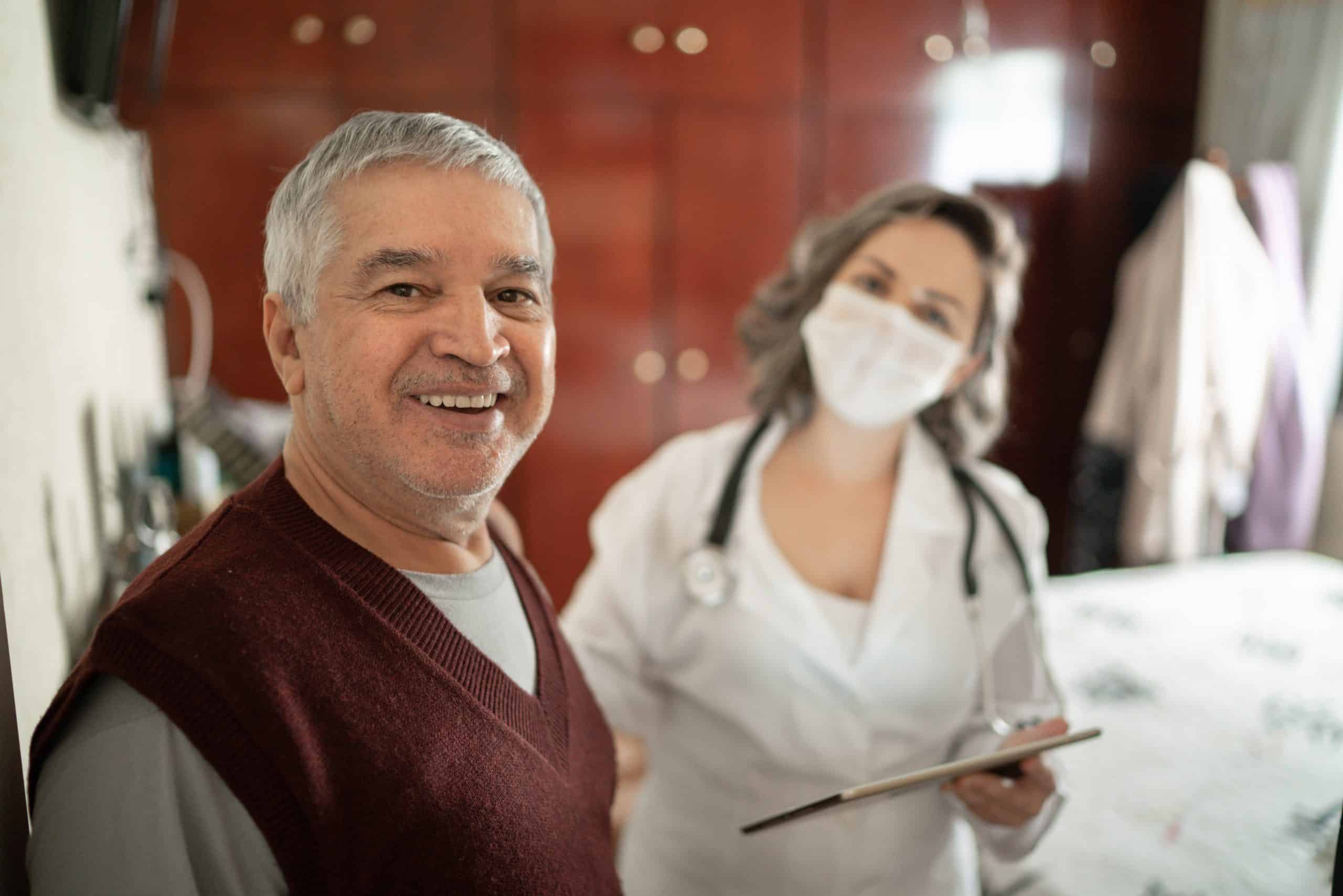 Portrait Of Health Visitor And Senior Man During Home Visit