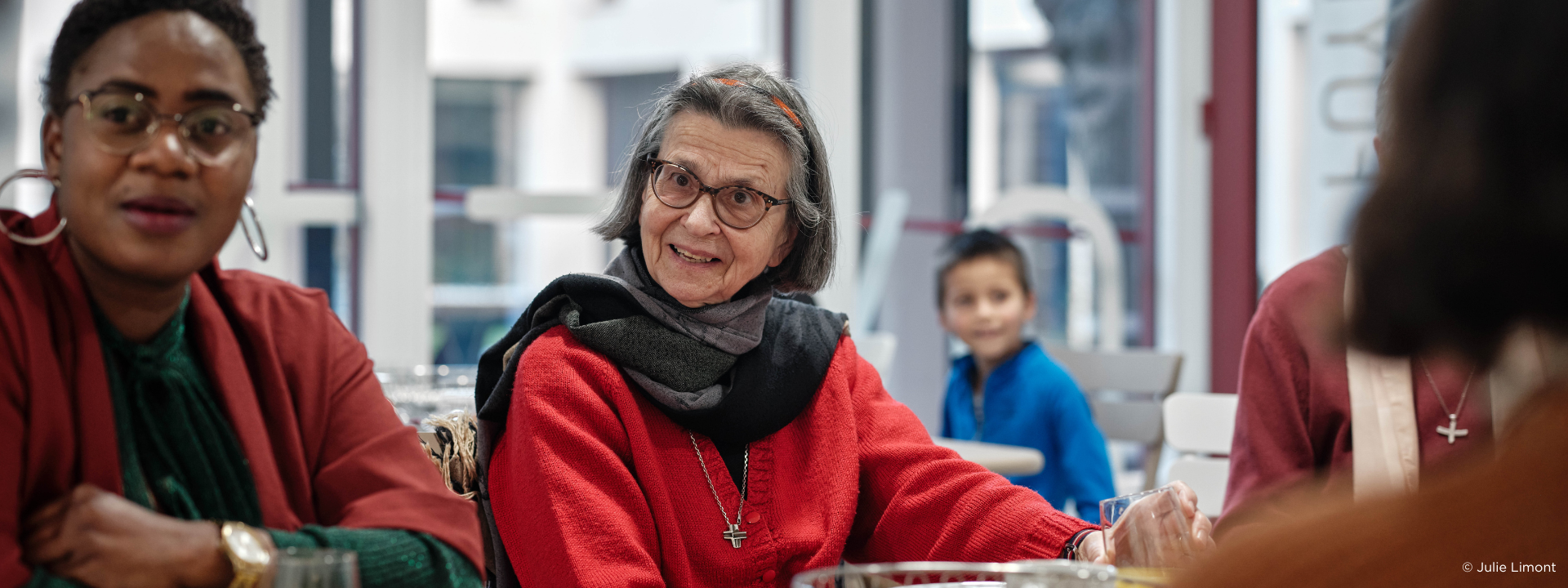 Jeune garçons, une senior et une jeune femme discutent ensemble en prenant le petit déjeuner
