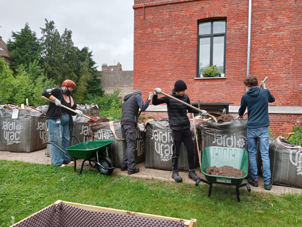 Groupe de quatre jeunes qui remplissent des brouettes avec de la terre