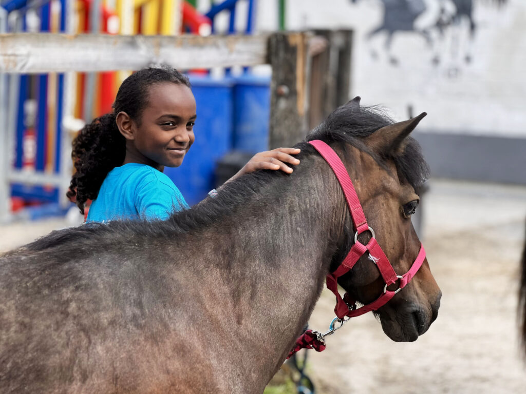 Petite fille souriante à côté de son poney